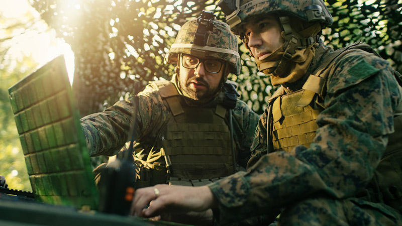 Military Staging Base, Officer Gives Orders to Chief Engineer, They Use Radio and Army Grade Laptop. They're in Camouflaged Tent in a Forest. They're on Reconnaissance Operation/ Mission.; Shutterstock ID 761939458; purchase_order: 110379711; job: Canada, US Civ, DOD; client: ; other: