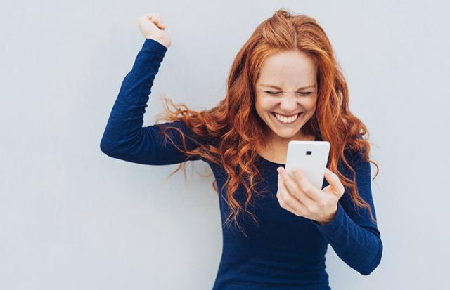 Frau mit Handy jubelt