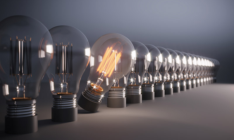 Glowing Light Bulb between the others. Can be used leadership, innovation and individuality concepts.  (3d render)