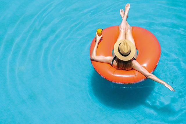 Frau mit Hut und Getränk im Pool