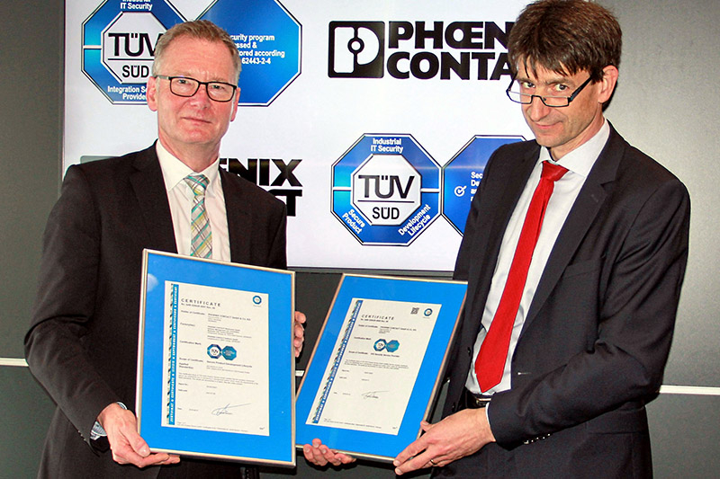 Roland Bent (CTO, Phoenix Contact) nimmt die Zertifikate von Jens Butenandt (CTO Product Service, TÜV Süd) entgegen.