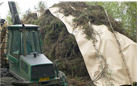 Die Biomasseabdeckung wird mit denselben Geräten, die auch zum Einsammeln der Holzreste verwenden werden, auf den Haufen gelegt.